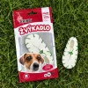Flat-lay shora na trávě: sáček Žvýkadlo s botičkou 204046 a vedle volně ležící bílá žvýkací botička se zeleným šněrováním 12,5 cm.