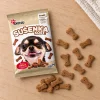 Flat-lay SKU 204602 (Akinu Kosti sušenka se zinkem 400 g) — sáček shora na světlém dubovém stole s rozloženými sušenkami, kompozice podle flat-lay 173011 (5e853864). Obal z BaseLinker (4ecaf563), surovina Helios doc 213274. 2k 1:1, vybrána v1 ze 2.