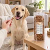 Lifestyle SKU 204603 (Akinu Kosti sušenka se zinkem 1 000 g) — obývák, labrador čeká na sušenku z ruky majitele, sáček na konferenčním stolku, evergreen, odpoledne, útulný mood. Maketa v Heliosu chybí — reference: sólo packshot a4745c6b (job ce4bbb7f) + BaseLinker foto 1be2e52c. 2k 1:1, vybrána v1 ze 2.