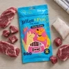 Flat-lay shora: sáček Jehněčí sendvič 176225 uprostřed, kolem syrové jehněčí maso (plátky + kostičky) a kousek tresky, podklad kuchyňská linka