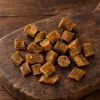 Solo surovina Akinu Masíčka Premium Heart & Eyes pamlsek pro kočky 50 g (282038) — hromádka hovězích masíček na rustikálním tmavém prkénku, teplé světlo. Kategorie pamlsek_psi_kocky, varianta p1 ze 4.