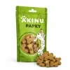 Packshot se surovinou Akinu PAPKY Kostička žlutá pamlsek pro psy 100 g (174027) — obal natočený podle vzoru 174027, vpravo dole před ním hromádka pamlsku. Styl jako řada Masíčka Premium.