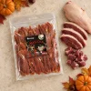 Flat-lay Masíčka 204945 (666 g, Halloween edice): plný sáček dle packshotu abb62b61, pouze syrové kachní maso asymetricky v jednom rohu, travertin, podzimní/halloweenský styling (mini dýně, listí, kaštany). Kompozice dle flat-laye 276faa55. Reference surovin AI-generovaná (HF job 41145f0b, 2,75 cr). Vybrána v1 ze 2.