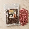 Flat-lay Masíčka 282061: plný 300g sáček dle e-shop packshotu 184cb0ab (maketa v Heliosu chybí), pouze syrové jehněčí asymetricky, travertin. Reference surovin AI-generovaná (HF job 254ac849, 2,75 cr).