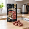 Sáček Kachní měkké kostky stojí na kuchyňské lince, vepředu hrstka kostek, ranní světlo