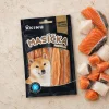 Flat-lay (Produkt + suroviny) pro Akinu Masíčka Premium Losos plátky s kůží 75 g na travertinovém podkladu, se syrovým lososem a treskou jako sekundární surovinou. Kompoziční reference pro řadu Masíčka Premium nebyla v Content DB nalezena (tag flat_lay_kompozice + akinu_masicka_premium), použit jen textový prompt.